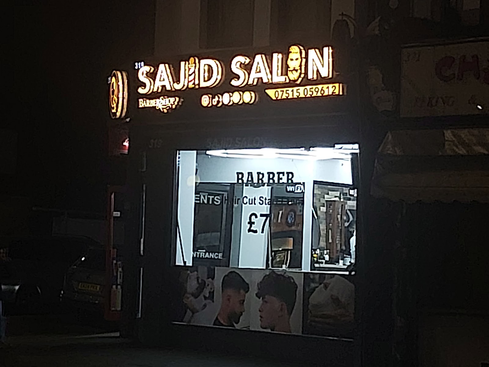The full width of the Sajid Salon shopfront at night
